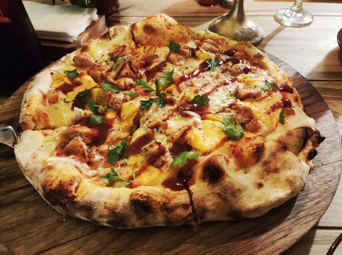 Artisan pizza baked in a clay oven, served on a wooden base